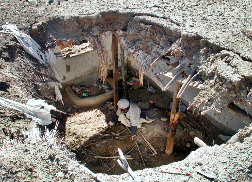 Damadola, PAKISTAN:  (FILES) In this picture taken 25 January 2006, a Pakistani tribesman sifts through the debris of his collapsed home after a 13 January, US air strike in the remote village of Damadola,in  Bajur Tribal Agency bordering Afghanistan.  Al-Qaeda deputy Ayman al-Zawahiri escaped death in a US missile strike last month on a remote tribal village bordering Afghanistan, Pakistani President Pervez Musharraf said. The January attack killed a close relative of al-Zawahiri and four other militants, Pakistan military spokesman Major General Shaukat Sultan quoted Musharraf as saying 12 February.  AFP PHOTO/Tariq MAHMOOD/FILES  (Photo credit should read TARIQ MAHMOOD/AFP/Getty Images)